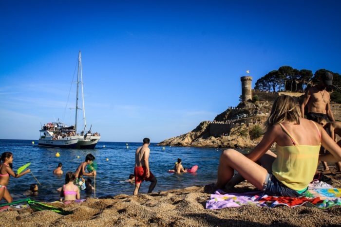 a group of people sitting on top of a sandy beach