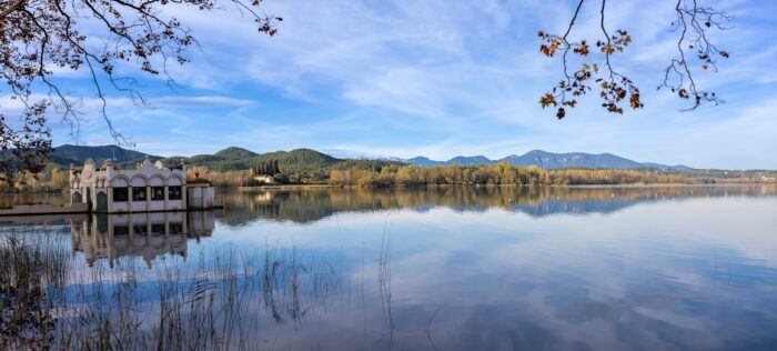 a lake surrounded by trees and mountains under a blue sky